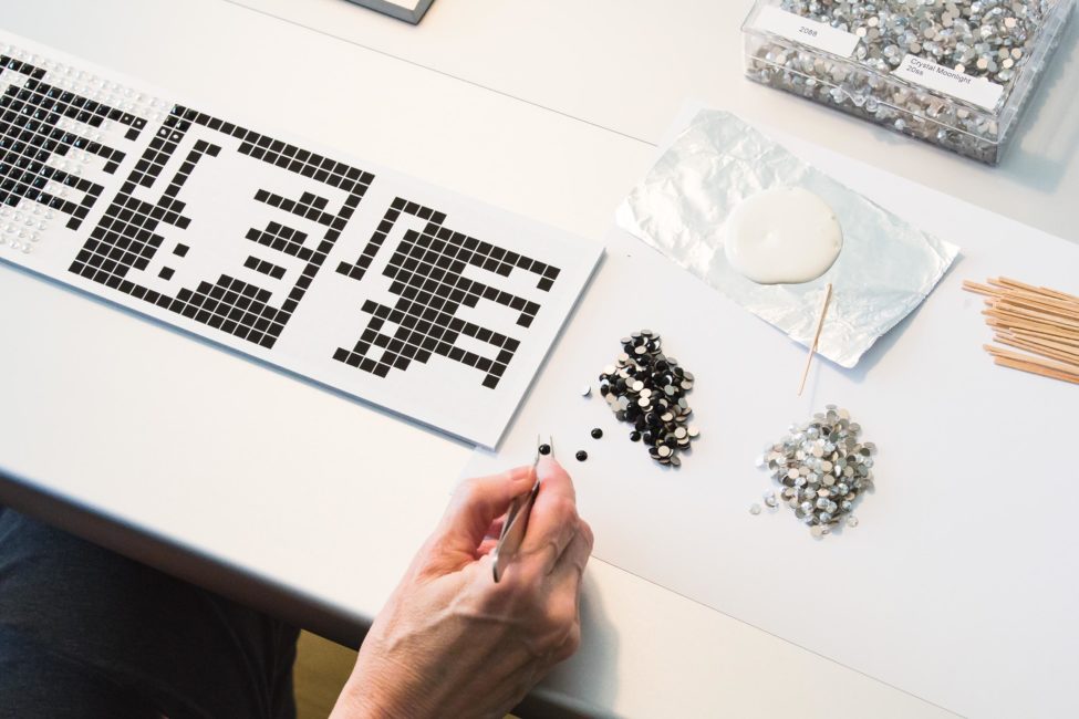 Julia Roshkow at work in her studio, glueing crystals to her artwork.